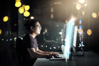 Man working at desktop computer in low light.