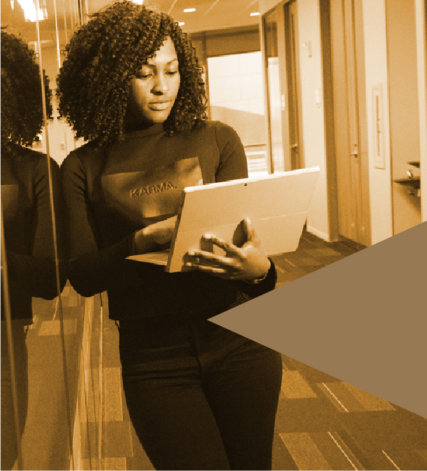 Woman leaning against server room with her laptop.
