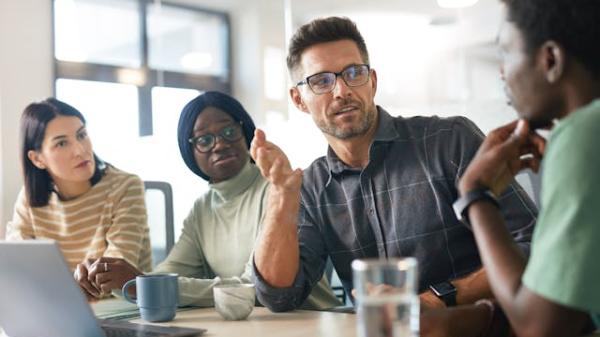 A diverse group of IT professionals engaged in a collaborative technical discussion, representing Deerfoot's commitment to inclusive sourcing and expert team building.