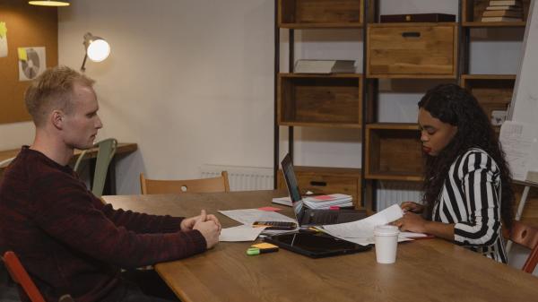 Manager and employee in a one-to-one meeting at a table in an office