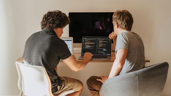 Two junior developers working through code together on a laptop