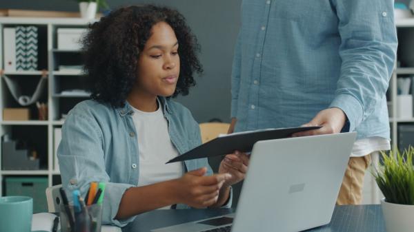 Hiring manager reviewing a document with a colleague at a laptop