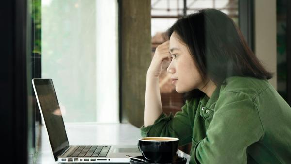 A woman thinking over a decision at her laptop