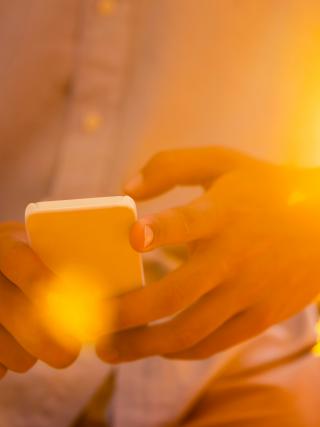 Sun burst effect close up image of man using a mobile phone.