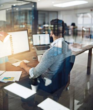 Man working in office surrounded by screens.