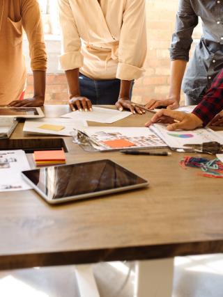 Colleagues stood, leaning on a table in concentration of the work laid out there.