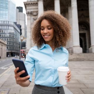Professional woman with phone and coffee in central London.