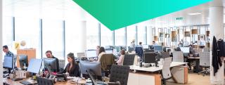 View of IT professionals at their desks working in a busy modern office environment.