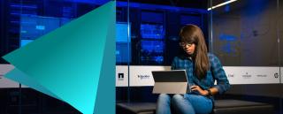 Female IT professional sat in an IT suite working at her laptop.