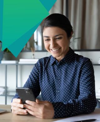 Female IT professional looking happy while reading her smart phone.