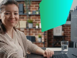Female IT worker looking happy while working on a laptop at her desk.