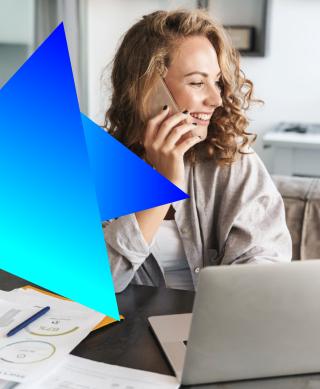 Female IT professional working on her laptop while on her mobile phone.