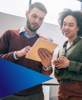 Male and female IT professionals in discussion while looking at a tablet device.