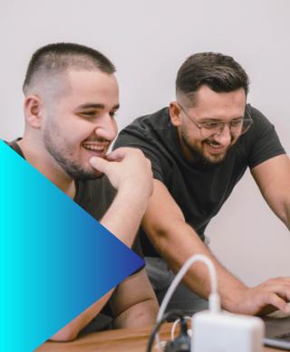 Two male IT professionals in discussion while looking at a desktop.