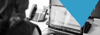Black and white photography of a female IT professional working on a laptop.