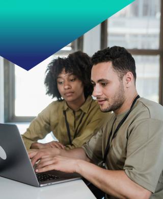 Male and Female IT professionals working together on a laptop.