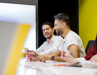 Two male professionals looking happy at work.