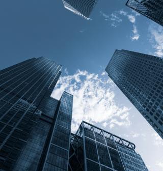 Low angle photo looking up at Canary Wharf buildings and blue sky