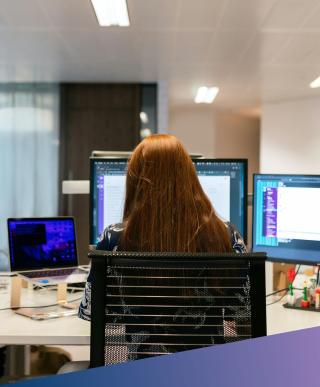 A specialist Machine Learning Engineer working on complex code across multiple monitors in a modern office environment.