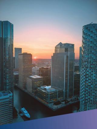 An elevated sunset view of the Canary Wharf financial district skyline in London, featuring major global banking headquarters, representing Deerfoot’s high-level strategic reach in Banking and Financial Services technology recruitment.