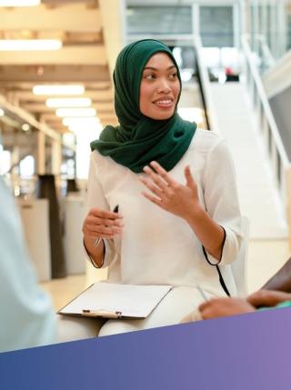 A senior female IT Project Leader wearing a green hijab leading a collaborative strategy session, representing Deerfoot’s commitment to diverse, high-impact leadership in project and programme management.
