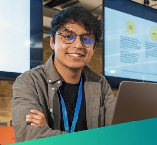 A smiling technical specialist in a modern office environment, representing the high-calibre, mission-aligned developers and engineers Deerfoot sources for critical UK public sector digital initiatives.