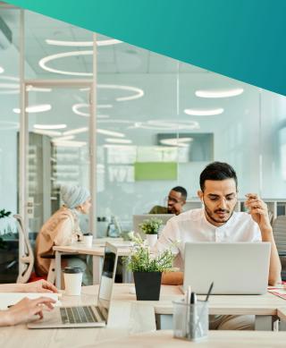 A modern, agile co-working office in the UK during Q2 2026, featuring diverse technical specialists working on laptops, reflecting the surging demand and collaborative culture of the InfoSec and Cyber Security talent market.