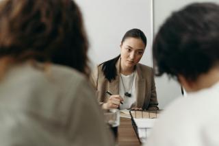Three women at a desk discussing work.