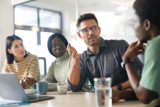 A diverse group of IT professionals engaged in a collaborative technical discussion, representing Deerfoot's commitment to inclusive sourcing and expert team building.