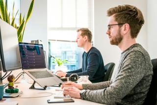 Two software developers working at desks in a bright office
