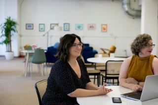 Two colleagues talking across a table in a bright office