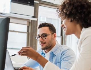Two colleagues working together at a computer in a bright office