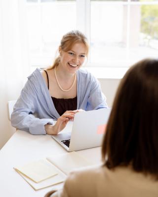 Recruitment consultant talking with a client across a table in a bright office