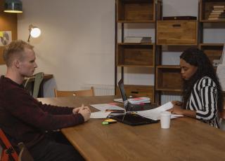 Manager and employee in a one-to-one meeting at a table in an office