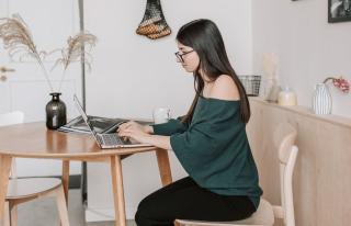 Woman working on a laptop at a kitchen table at home