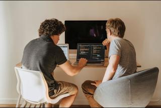 Two junior developers working through code together on a laptop