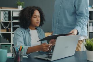 Hiring manager reviewing a document with a colleague at a laptop
