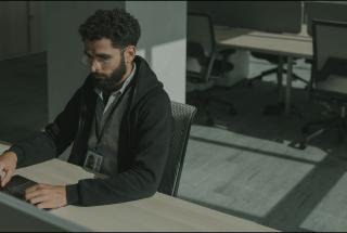 Security engineer with an ID badge working at a laptop in an office