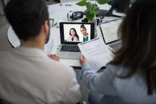 Two interviewers reviewing paperwork during an online job interview