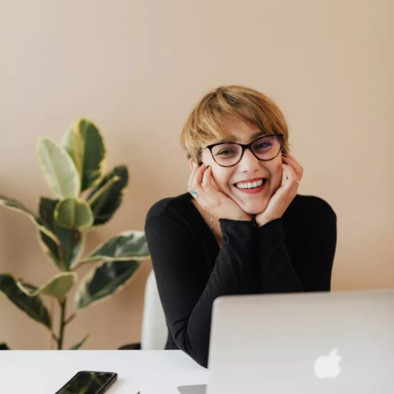 woman in front of a laptop smiling