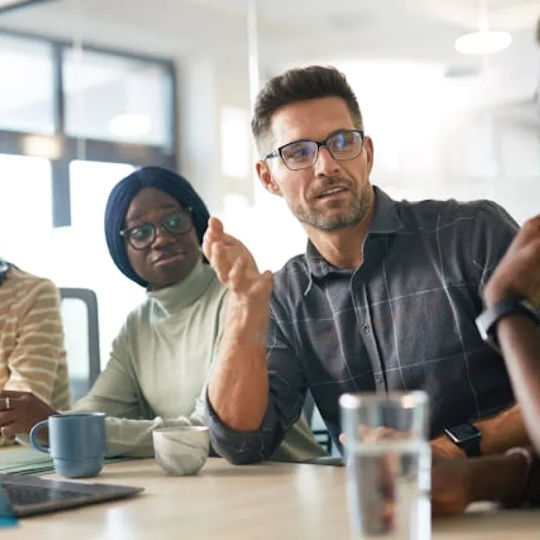 A diverse group of IT professionals engaged in a collaborative technical discussion, representing Deerfoot's commitment to inclusive sourcing and expert team building.
