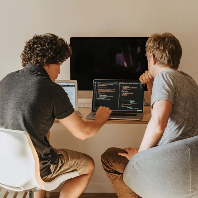 Two junior developers working through code together on a laptop