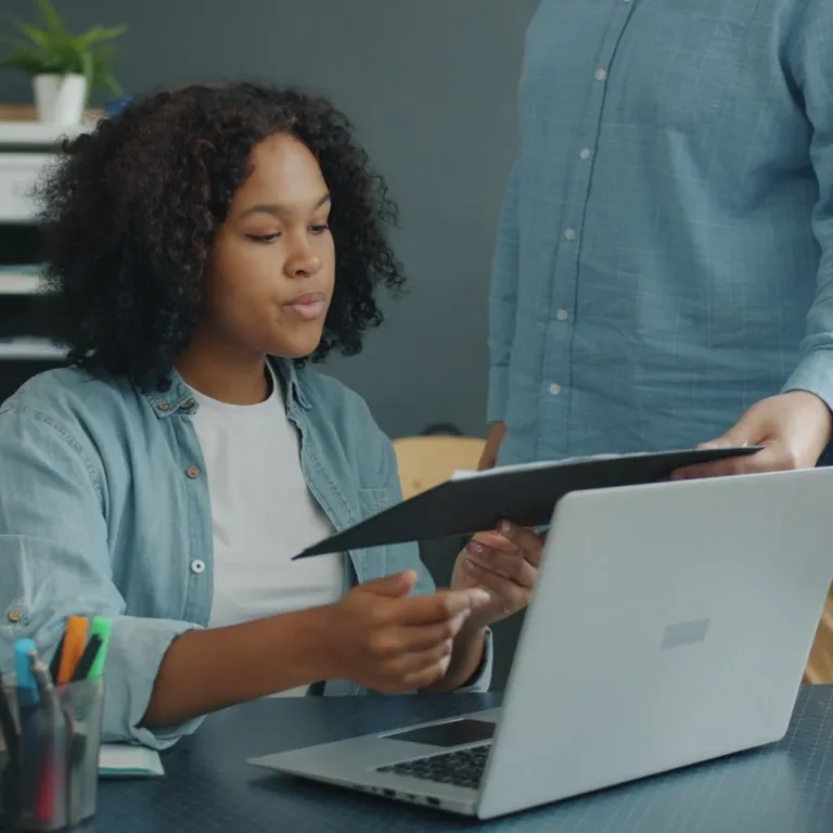 Hiring manager reviewing a document with a colleague at a laptop