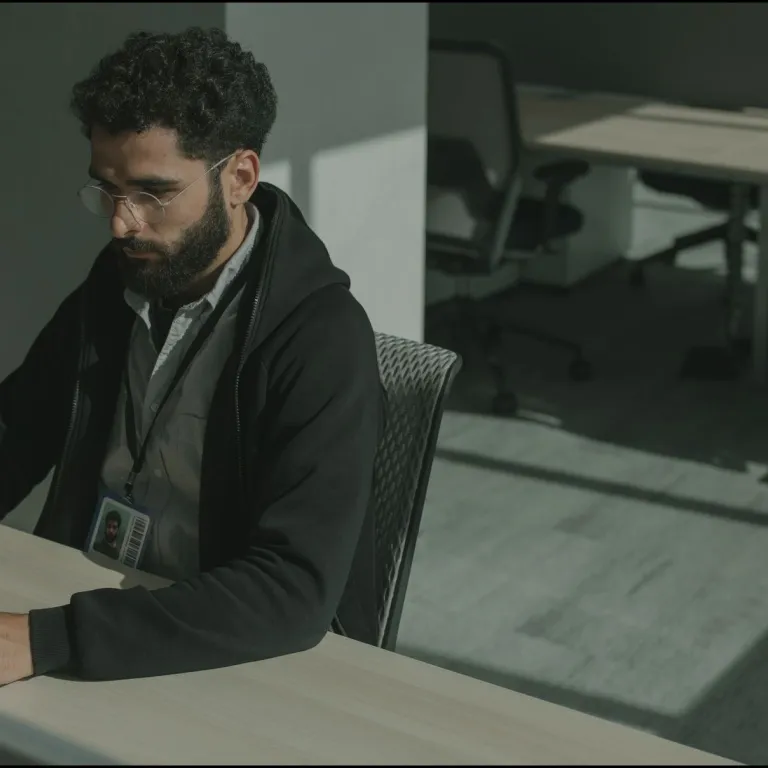 Security engineer with an ID badge working at a laptop in an office