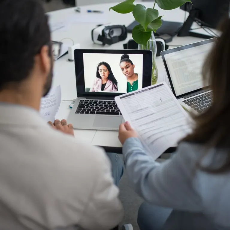 Two interviewers reviewing paperwork during an online job interview