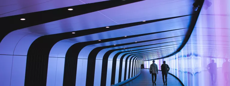 Two men walking down a modern office walkway.